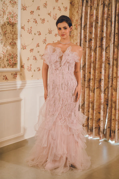 A lavender ruffled gown adorned with sequins, pearls, and crystal accents, layered in delicate tulle. Designed for fluid movement and radiant sparkle. Perfect for cocktail nights and statement celebrations.