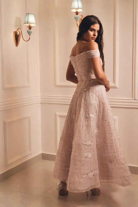 A lavender off-shoulder gown with floral appliqué and crystal detailing, flowing gracefully with timeless charm. Designed for soirées, weddings, and modern celebrations.