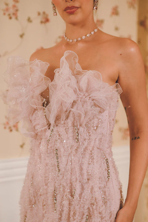A lavender ruffled gown adorned with sequins, pearls, and crystal accents, layered in delicate tulle. Designed for fluid movement and radiant sparkle. Perfect for cocktail nights and statement celebrations.