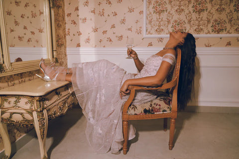 A lavender off-shoulder gown with floral appliqué and crystal detailing, flowing gracefully with timeless charm. Designed for soirées, weddings, and modern celebrations.