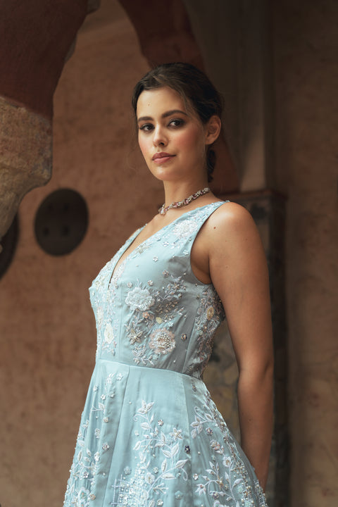 A powder-blue gown adorned with sequins and floral embroidery, designed with a V- neck for modern royalty. Flowing with effortless movement, it’s crafted for statement evenings, soirées, weddings, and modern celebrations.